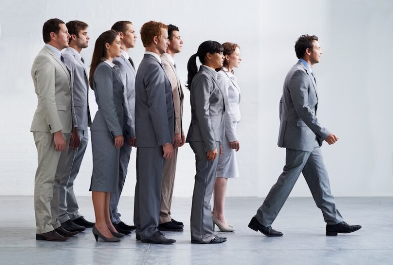 A young business manager walking ahead of his colleagues