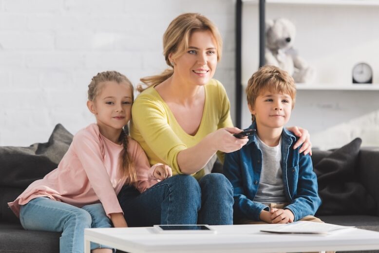 happy mother using remote controller and watching tv together at home
