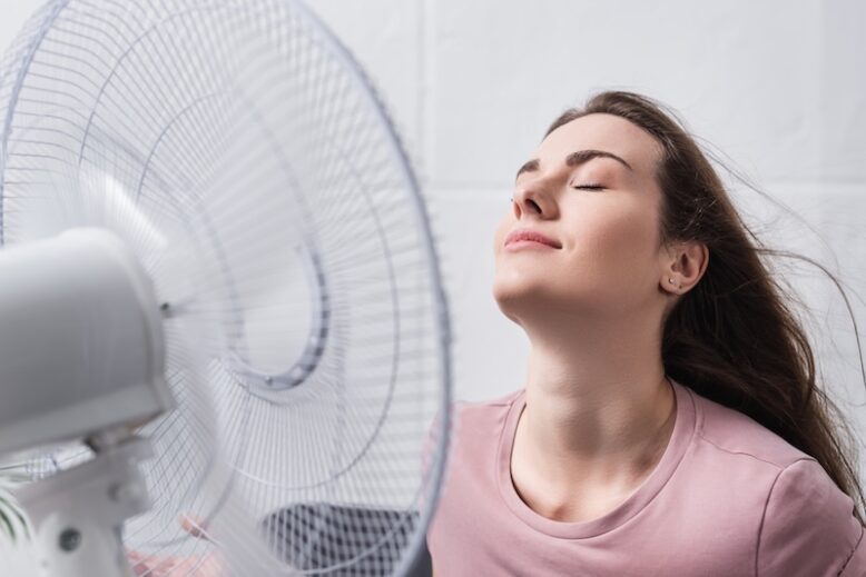 girl feeling comfortable with electric fan at home during summer heat